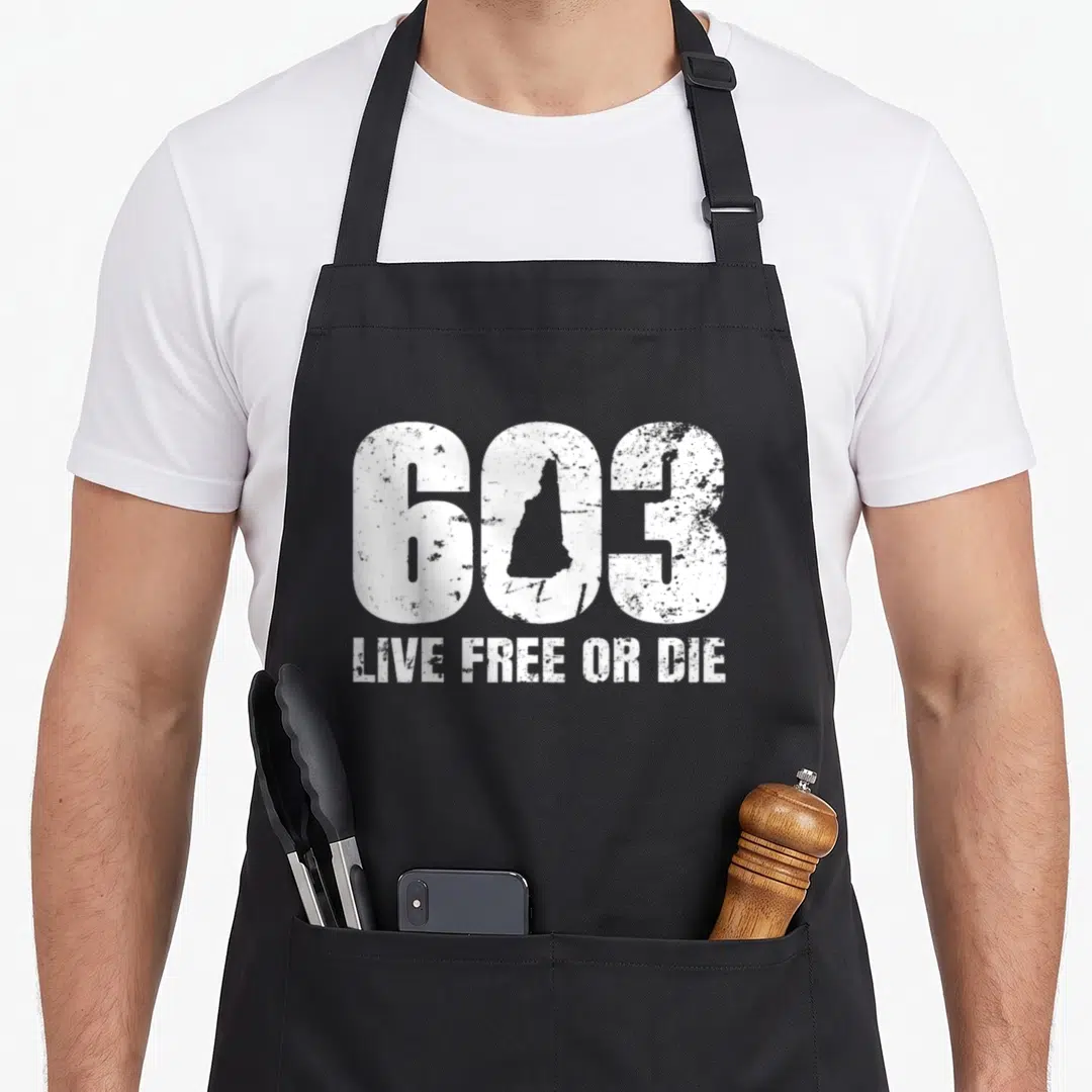 Hampshire apron or apron - White 603 distressed text with New Hampshire state outline inside the zero and Live Free — shown on a black cotton canvas apron against a white background