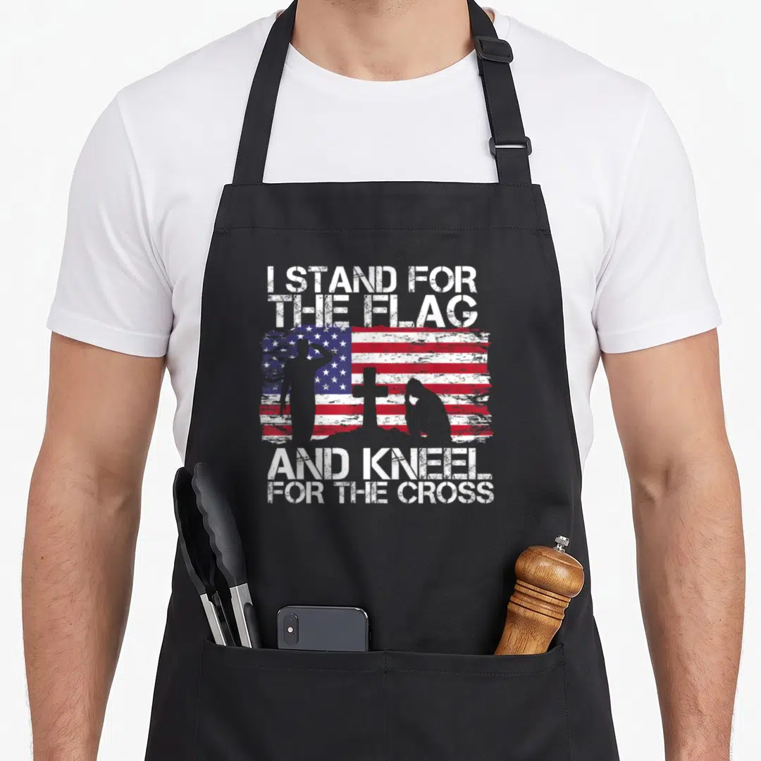 Flag cross apron - Distressed USA flag with saluting, cross, and kneeling silhouettes and white text — shown on a black cotton canvas apron against a white background