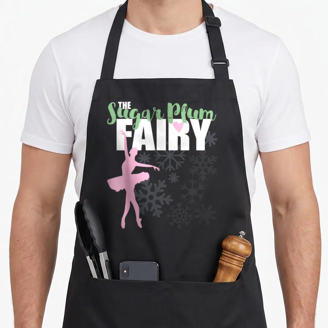 Sugar nutcracker apron - The Sugar Plum FAIRY text with pink heart and ballerina silhouette — shown on a black cotton canvas apron against a white background