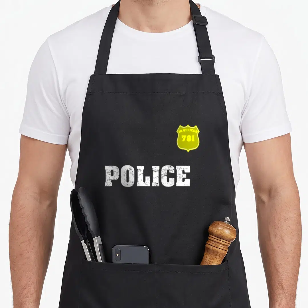Officer halloween apron - Yellow badge with JR.OFFICER 781 and white POLICE text on canvas — shown on a black cotton canvas apron against a white background