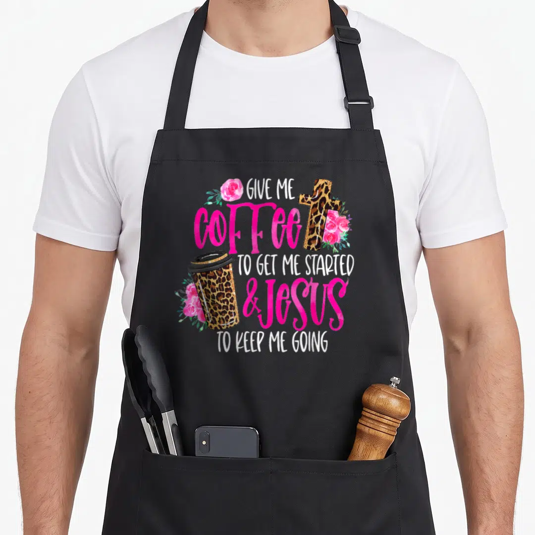 Jesus coffee apron - Stacked text with leopard coffee cup cross and pink roses on canvas — shown on a black cotton canvas apron against a white background