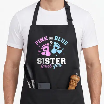 Gender sister apron - Pink and blue baby footprints with PINK OR BLUE text and SISTER loves you message — shown on a black cotton canvas apron against a white background