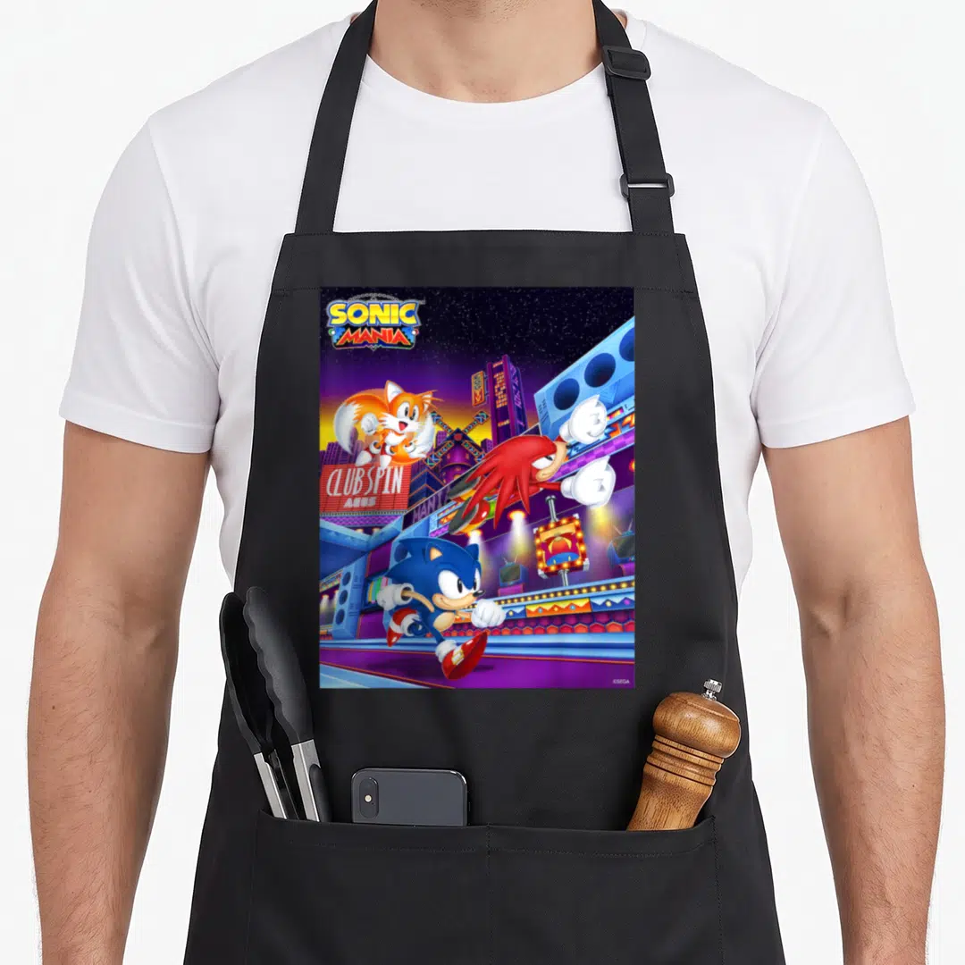 Mania crazy hedgehog man apron - Sonic running right with Knuckles leaping and Tails near a purple city sign reading — shown on a black cotton canvas apron against a white background