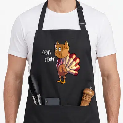Thanksgiving cat funny turkey apron - Cartoon turkey in tan cat box head next to white MEOW MEOW text — shown on a black cotton canvas apron against a white background