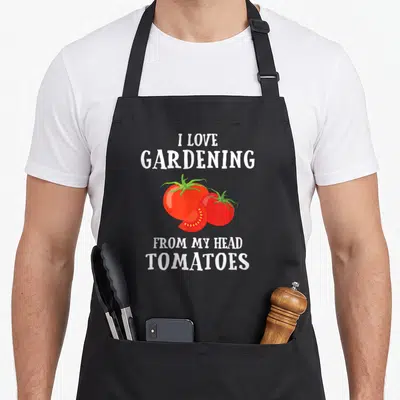 Gardener vegetable apron - I love gardening from my head tomatoes pun with two whole and one sliced red tomato — shown on a black cotton canvas apron against a white background