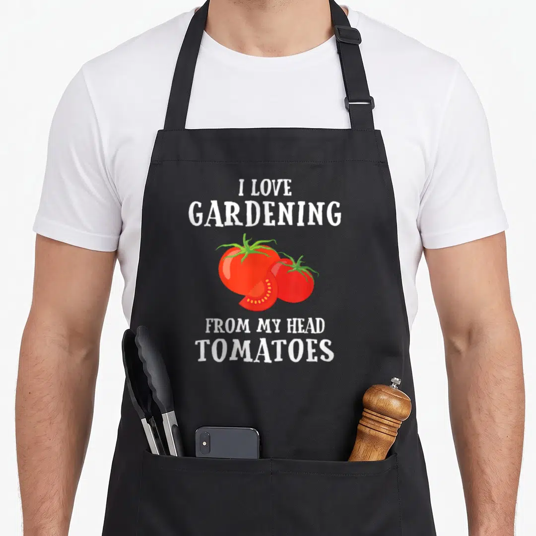 Gardener vegetable apron - I love gardening from my head tomatoes pun with two whole and one sliced red tomato — shown on a black cotton canvas apron against a white background