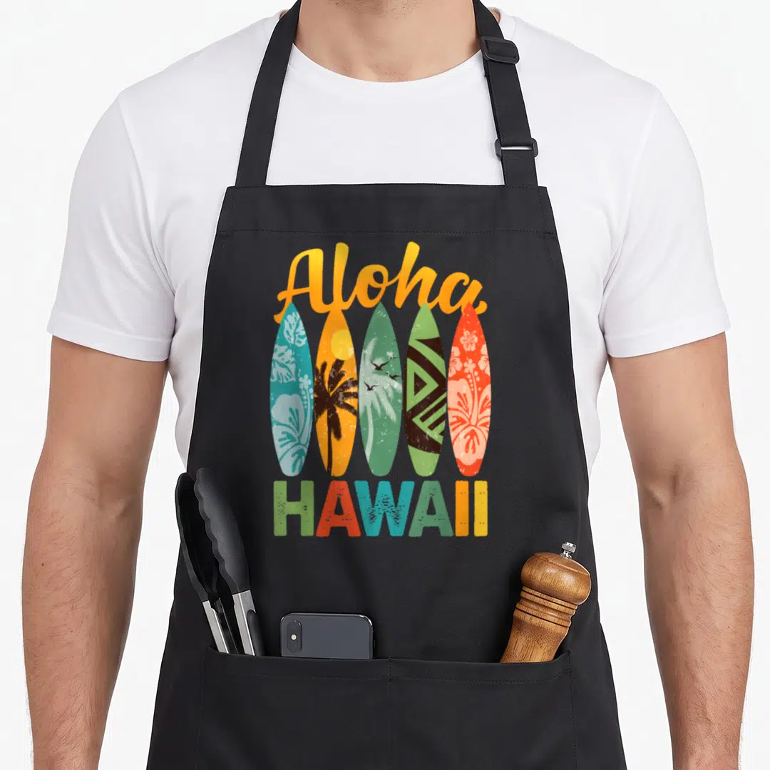 Surfboard hawaiian apron - Five vertical surfboards in yellow orange green blue red with Aloha and HAWAII text — shown on a black cotton canvas apron against a white background
