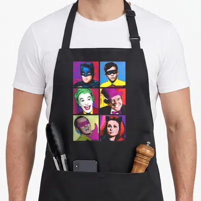 Pop tv apron - Six character portraits in a 3x2 grid of colorful squares in retro style — shown on a black cotton canvas apron against a white background