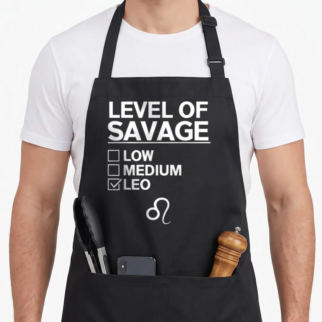 Vintage leo zodiac aprons - White Level of Savage checklist with Leo checked and zodiac symbol at bottom — shown on a black cotton canvas apron against a white background