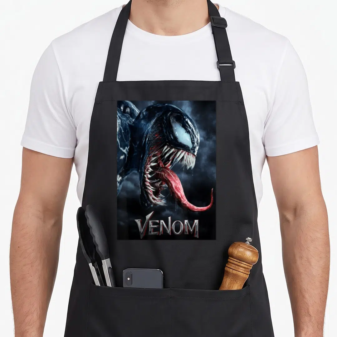 Tongue novelty apron - Venom head with open mouth, long red tongue, and silver VENOM text — shown on a black cotton canvas apron against a white background