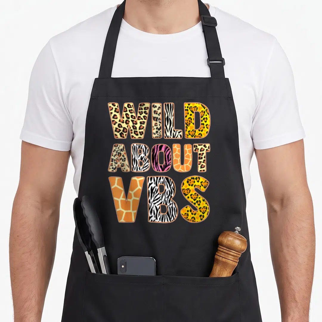 Wild vacation bible school apron - WILD ABOUT VBS text filled with leopard zebra and giraffe animal prints — shown on a black cotton canvas apron against a white background