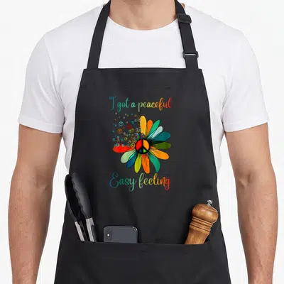 Easy sunflower apron - Rainbow flower with peace sign center and split text I got a peaceful Easy feeling — shown on a black cotton canvas apron against a white background