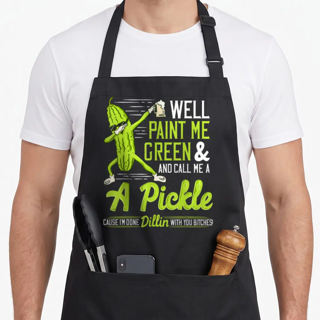 Well paint apron - Cartoon pickle dabbing with beer mug and dill pun text — shown on a black cotton canvas apron against a white background