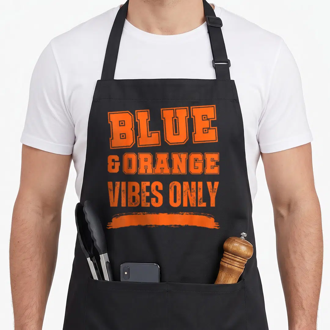 Blue game aprons - Orange blocky athletic text reading BLUE & ORANGE VIBES ONLY with a distressed brushstroke underline — shown on a black cotton canvas apron against a white background