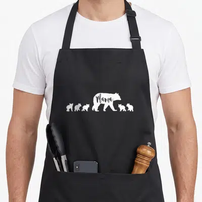 Five cute bear apron - White Mama bear silhouette with five cubs and text cutout — shown on a black cotton canvas apron against a white background