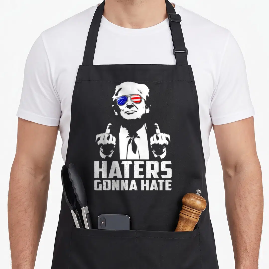 Hater middle apron - Man with flag sunglasses and two middle fingers above HATERS GONNA HATE text — shown on a black cotton canvas apron against a white background