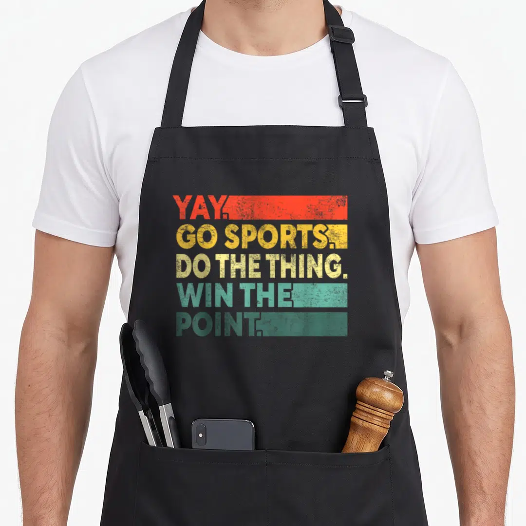 Yay vintage sports apron - Stacked text YAY GO SPORTS DO THE THING WIN THE POINT on red yellow teal distressed strips — shown on a black cotton canvas apron against a white background