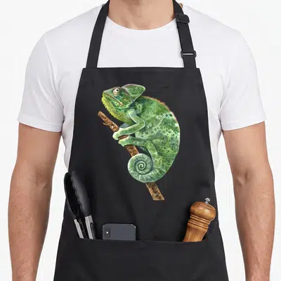 Chameleon crew apron - Green watercolor chameleon perched on a brown branch with a curled tail — shown on a black cotton canvas apron against a white background