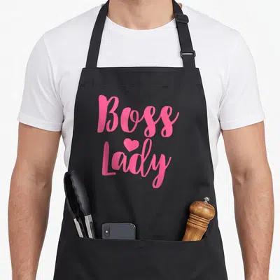 Boss business apron - Pink script text reading Boss Lady with a small heart centered between the words — shown on a black cotton canvas apron against a white background