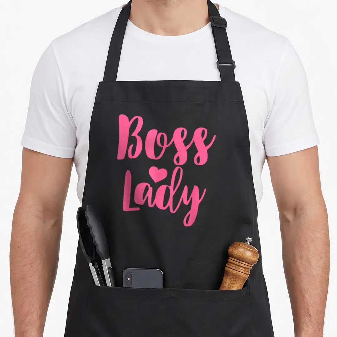 Boss business apron - Pink script text reading Boss Lady with a small heart centered between the words — shown on a black cotton canvas apron against a white background