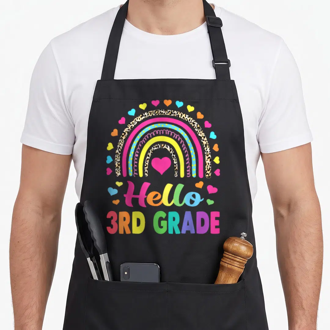 Hello leopard aprons - Rainbow with leopard print bands and pink heart above Hello 3rd Grade text — shown on a black cotton canvas apron against a white background