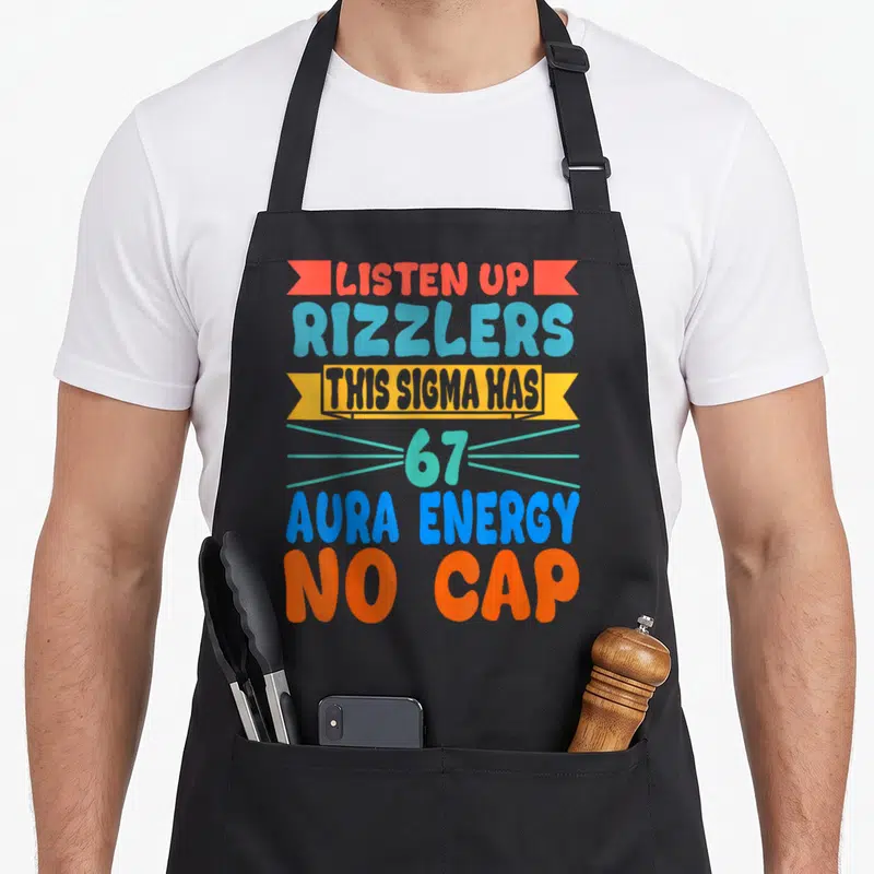 Listen days christmas apron - Orange ribbons and blue text reading Listen Up Rizzlers Sigma Has 67 Aura Energy No Cap — shown on a black cotton canvas apron against a white background