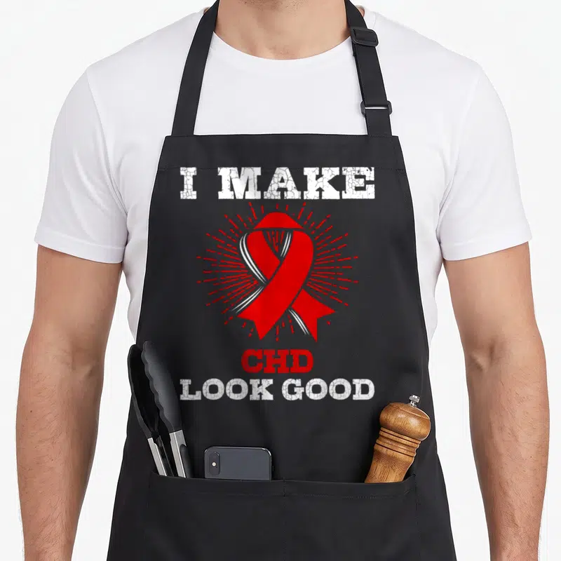 Funny chd congenital heart defect apron - Red awareness ribbon with sunburst and distressed I Make CHD Look Good text — shown on a black cotton canvas apron against a white background