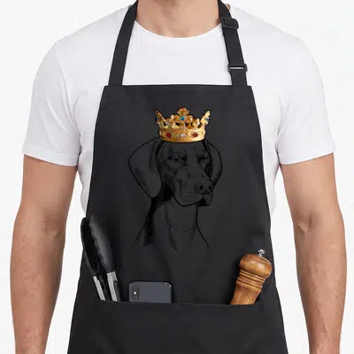 German dog wearing apron - Line art dog head with gold crown and jewels on black white background — shown on a black cotton canvas apron against a white background