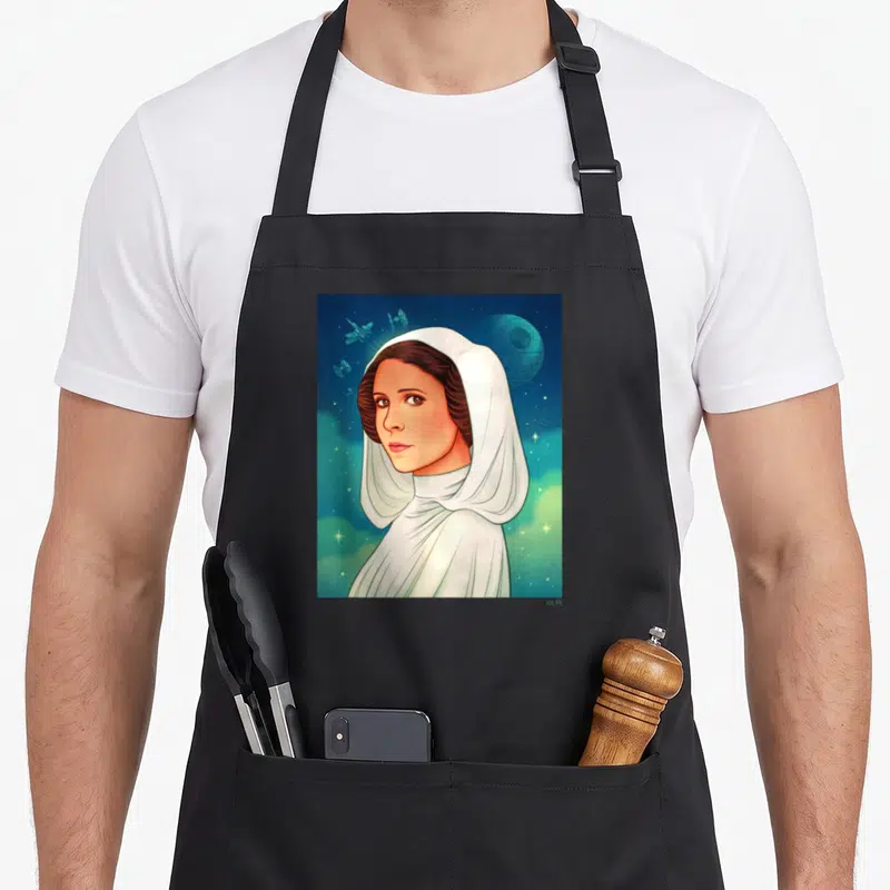 Exclusive new hope apron - Princess Leia white hooded gown space background Death Star TIE fighters cartoon art — shown on a black cotton canvas apron against a white background