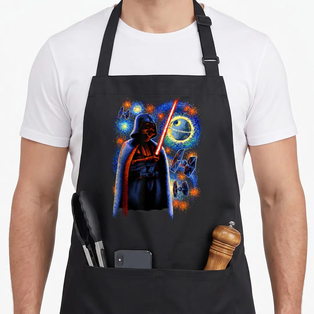 Death starry night apron - Darth Vader holding red lightsaber surrounded by swirling blue stars, Death Star, and three — shown on a black cotton canvas apron against a white background
