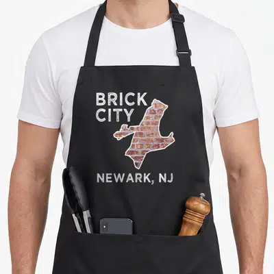 Brick newark new jersey apron - Brick-filled Newark map outline with weathered BRICK CITY and NEWARK NJ text in white — shown on a black cotton canvas apron against a white background