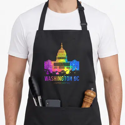 Washington us aprons - Rainbow watercolor US Capitol Building with WASHINGTON DC UNITED STATES text and paint splatters — shown on a black cotton canvas apron against a white background