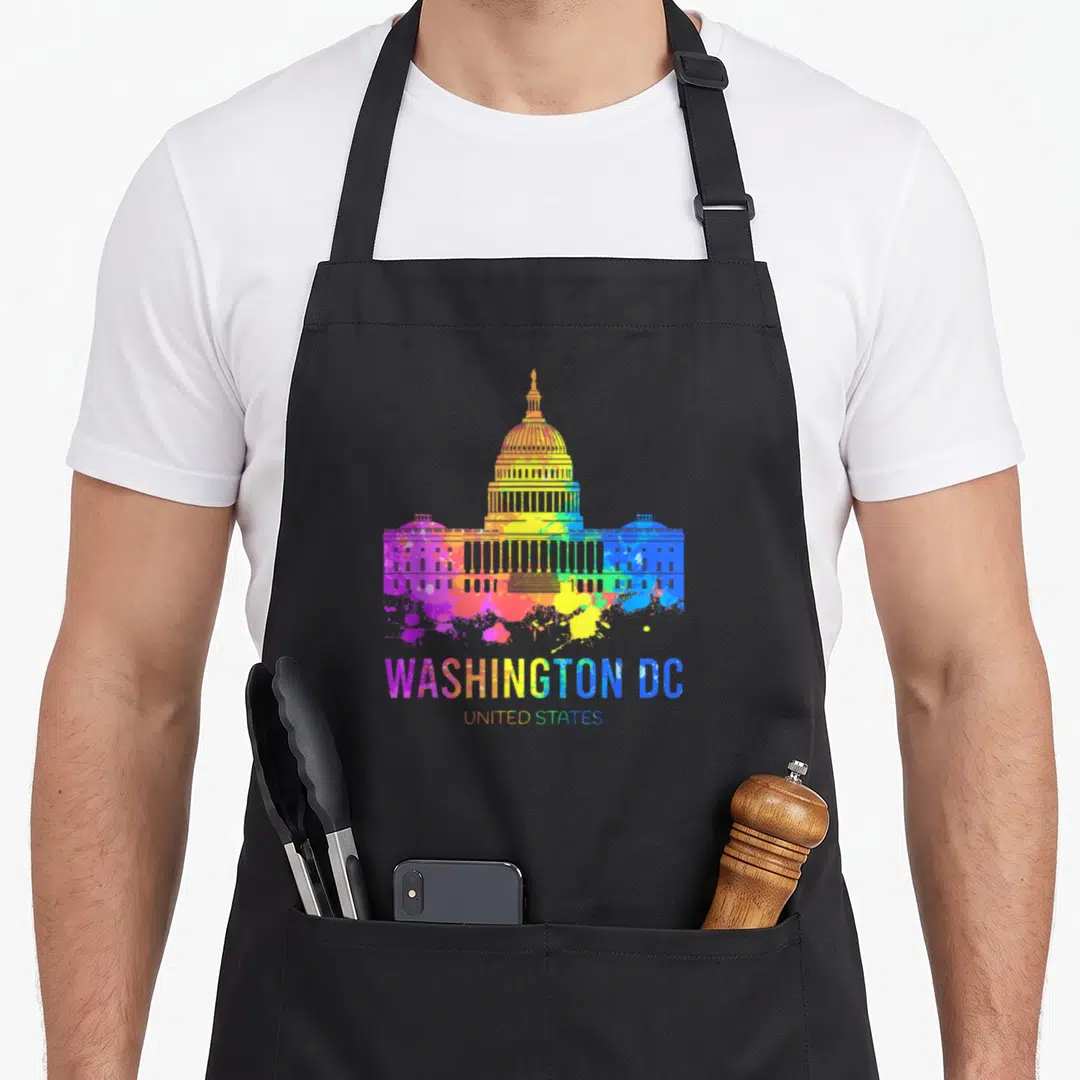 Washington us aprons - Rainbow watercolor US Capitol Building with WASHINGTON DC UNITED STATES text and paint splatters — shown on a black cotton canvas apron against a white background