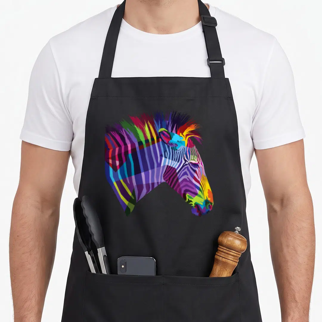 Rainbow zebra apron - Cartoon zebra head with blue purple green yellow and red stripes — shown on a black cotton canvas apron against a white background