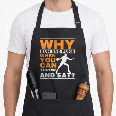 Run throwers apron - Distressed orange and white text Why Run and Puke with white discus player silhouette — shown on a black cotton canvas apron against a white background