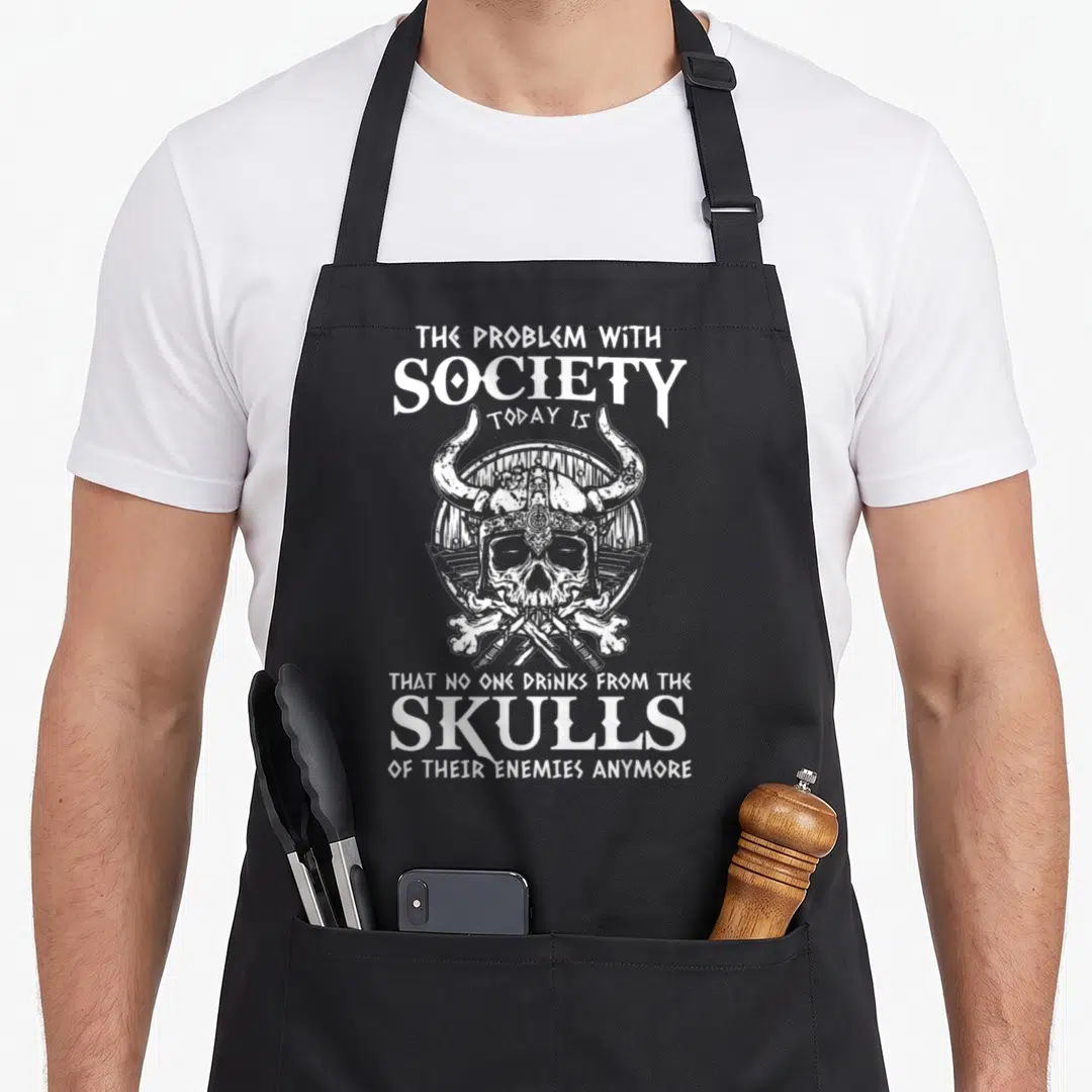 Society viking apron - White skull in horned viking helmet with crossed bones and sarcastic text about enemy skulls — shown on a black cotton canvas apron against a white background