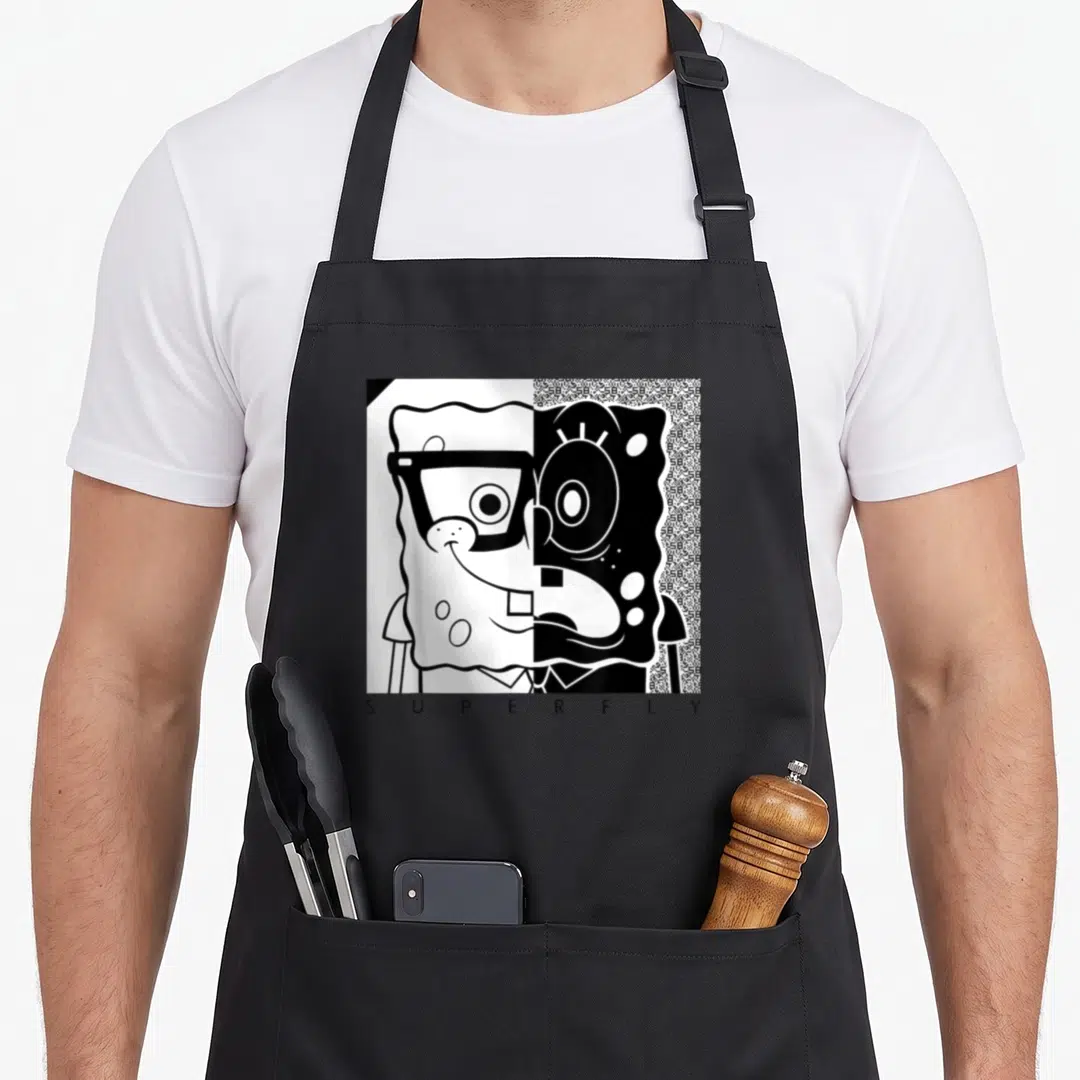Squarepant white apron - Black and white split face SpongeBob with superfly text below — shown on a black cotton canvas apron against a white background