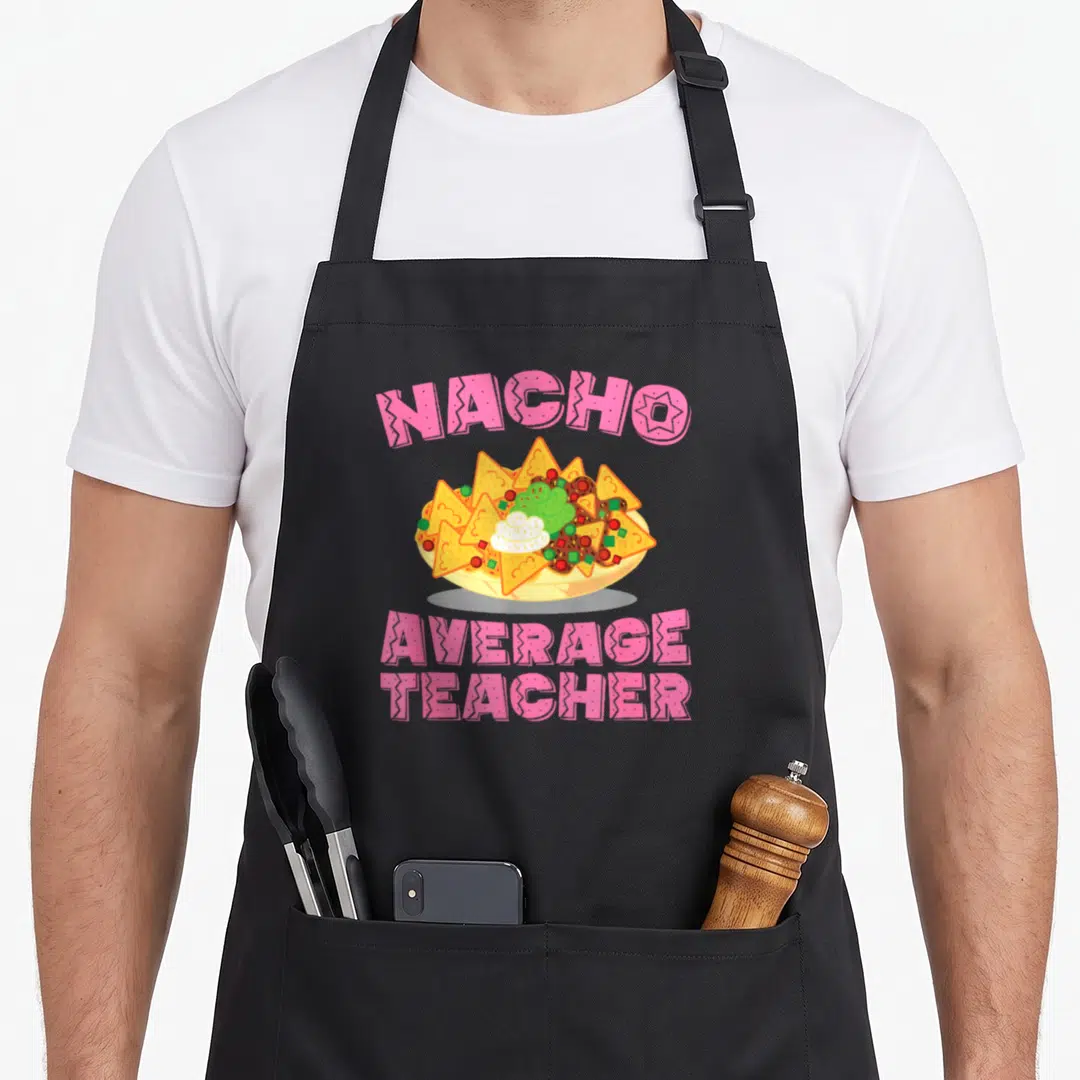 Nacho teacher apron - Pink arched text reading NACHO AVERAGE TEACHER above a cartoon bowl of nachos with green — shown on a black cotton canvas apron against a white background