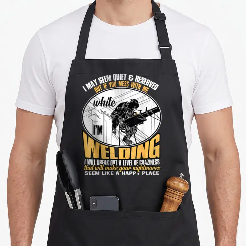 Welding mess apron - Welder figure in circle with sarcastic text about not messing with them while welding — shown on a black cotton canvas apron against a white background