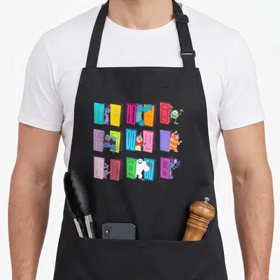 Funny door apron - Nine cartoon monsters standing beside blue red yellow green purple doors in a grid — shown on a black cotton canvas apron against a white background