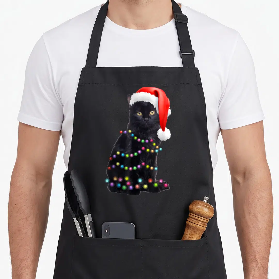 Cat christmas lights apron - Black cat wearing red and white santa hat wrapped in multi-colored christmas lights — shown on a black cotton canvas apron against a white background