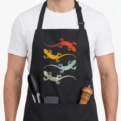 Reptile gecko apron - Four lizards in orange, yellow, blue, and white stacked vertically facing opposite directions — shown on a black cotton canvas apron against a white background