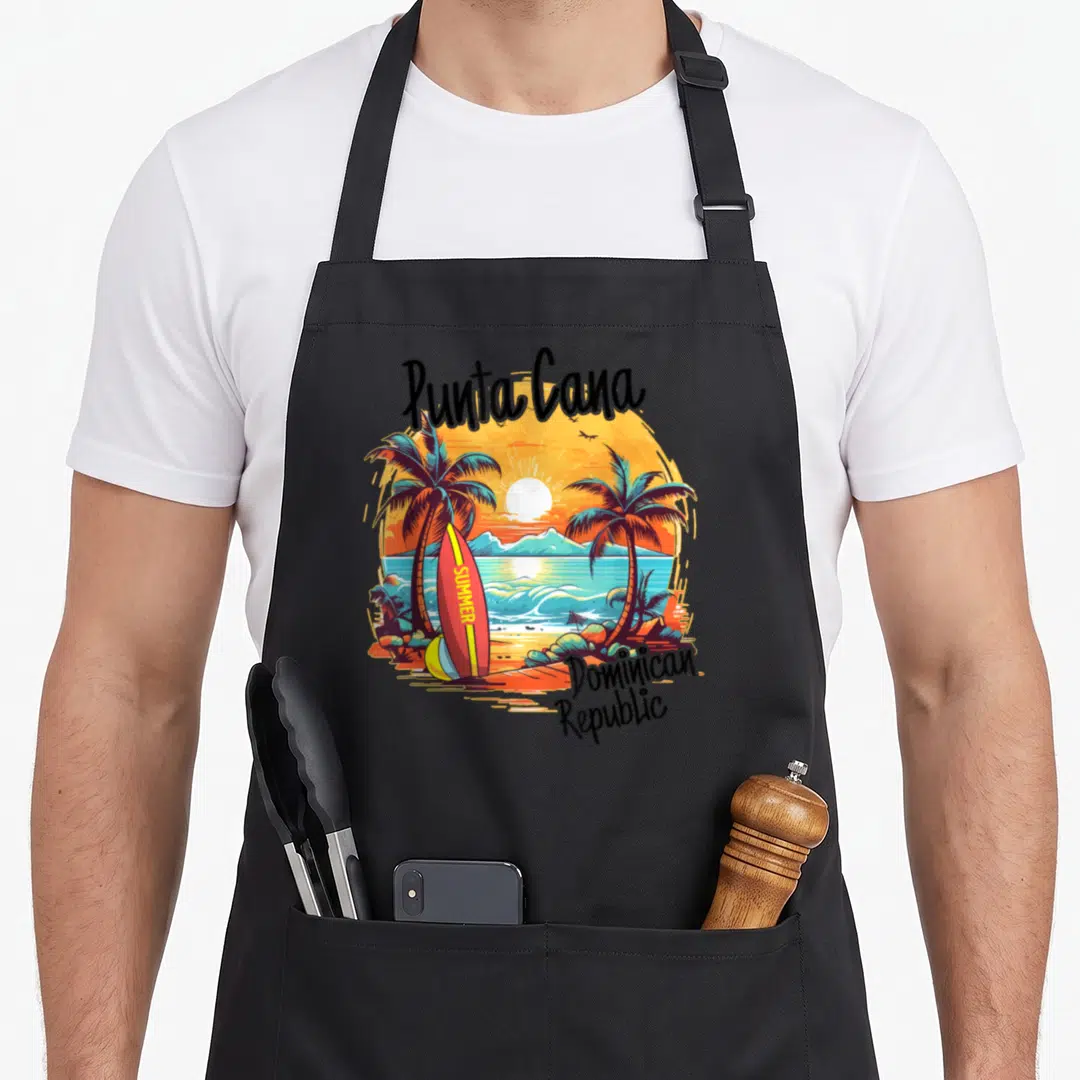 Punta family aprons - Punta Cana arched text, summer surfboard, palm trees, sunset, Dominican Republic label — shown on a black cotton canvas apron against a white background
