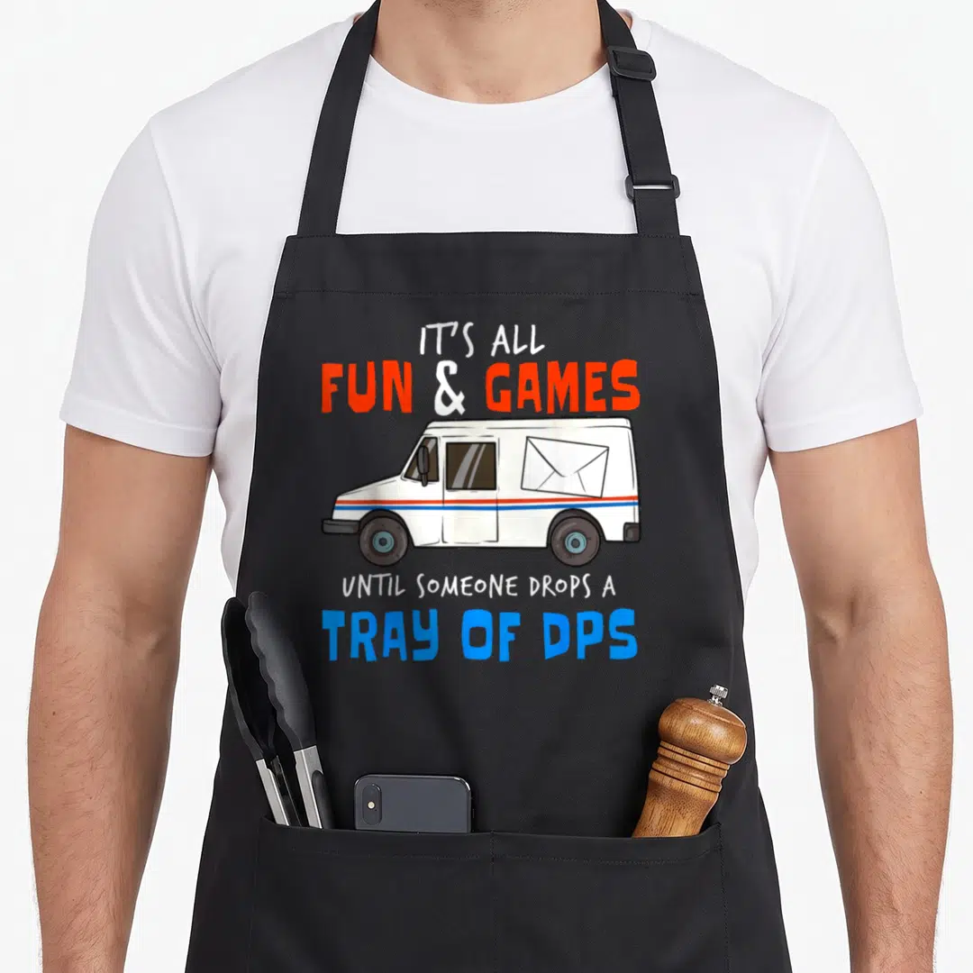 Drop post apron - Cartoon van with envelope and text IT'S ALL FUN & GAMES UNTIL SOMEONE DROPS A TRAY OF DPS in white — shown on a black cotton canvas apron against a white background