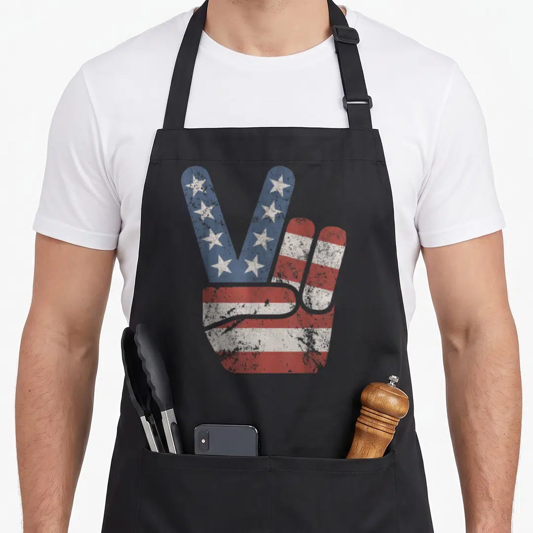 Peace american flag apron - Distressed hand peace sign filled with red white blue stars and stripes pattern — shown on a black cotton canvas apron against a white background