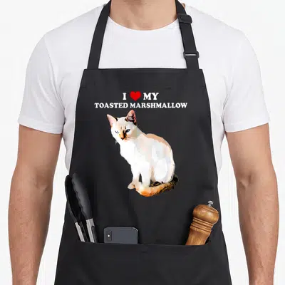 Toasted cat apron - I Love My Toasted Marshmallow text with red heart and white orange flame point Siamese cat photo — shown on a black cotton canvas apron against a white background
