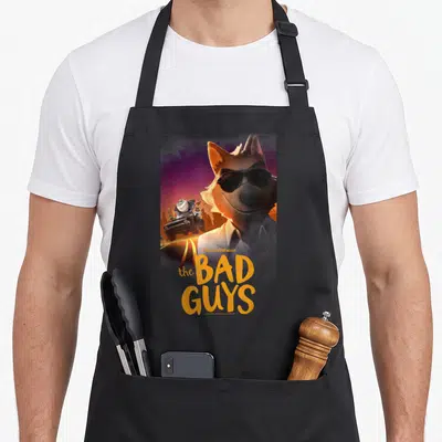 Wolf mr apron - Fox wearing sunglasses with The Bad Guys text and getaway car in orange and purple — shown on a black cotton canvas apron against a white background