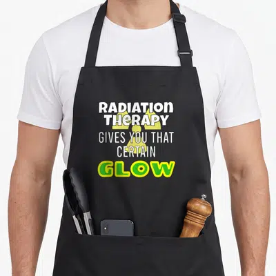 Glow radiation aprons - Stacked white and lime green text over a yellow radiation symbol — shown on a black cotton canvas apron against a white background