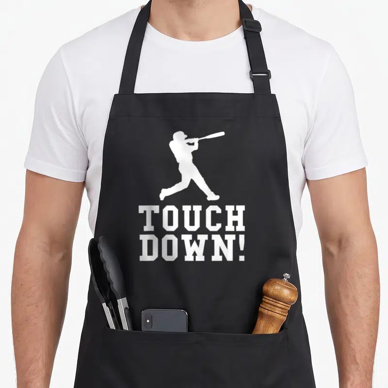 Touchdown football apron - White baseball batter silhouette above stacked text TOUCH DOWN! — shown on a black cotton canvas apron against a white background
