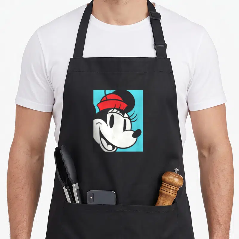 Portrait essential apron - Cartoon mouse head with red bow on blue background — shown on a black cotton canvas apron against a white background